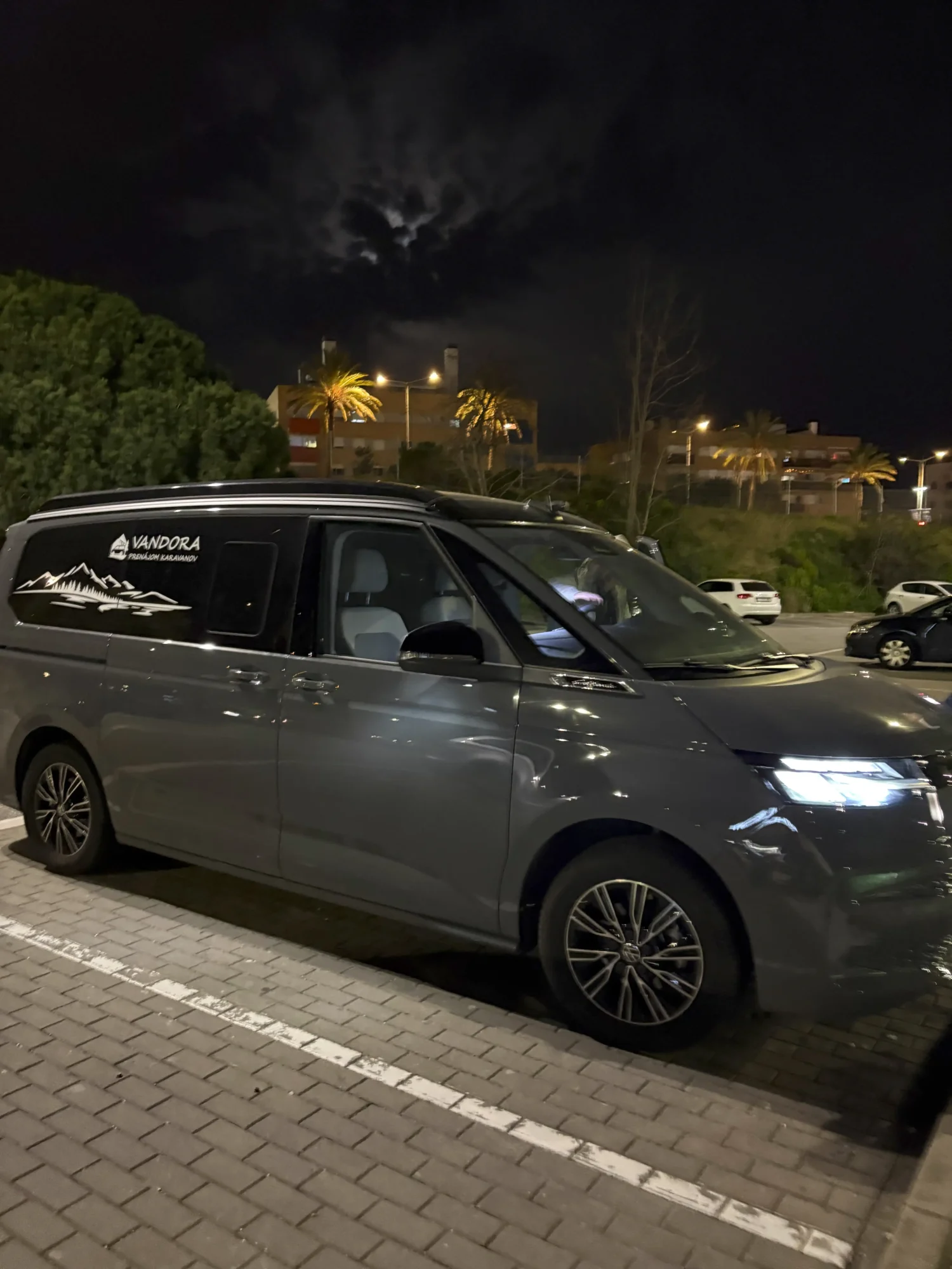 Campervan VANDORA zaparkovaný večer pri obchodnom centre počas roadtripu pri Barcelone
